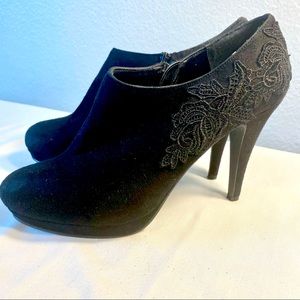 Platform heeled bootie in black velvet with lace appliqué trim.